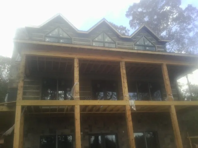 Dormers and porch framing on a large log home under construction — Roof Coating work by our crew in Holton