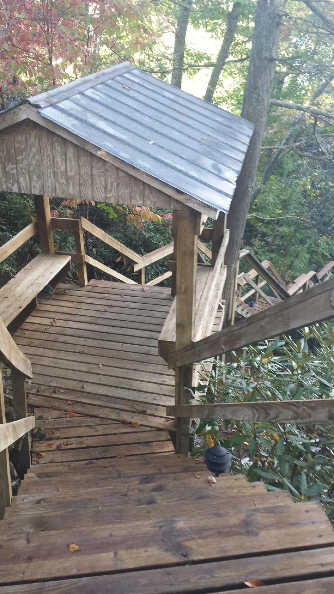 Metal roofed shelter over wooden steps on a wooded walkway — Skylight Repair & Installation work by our crew in Holton